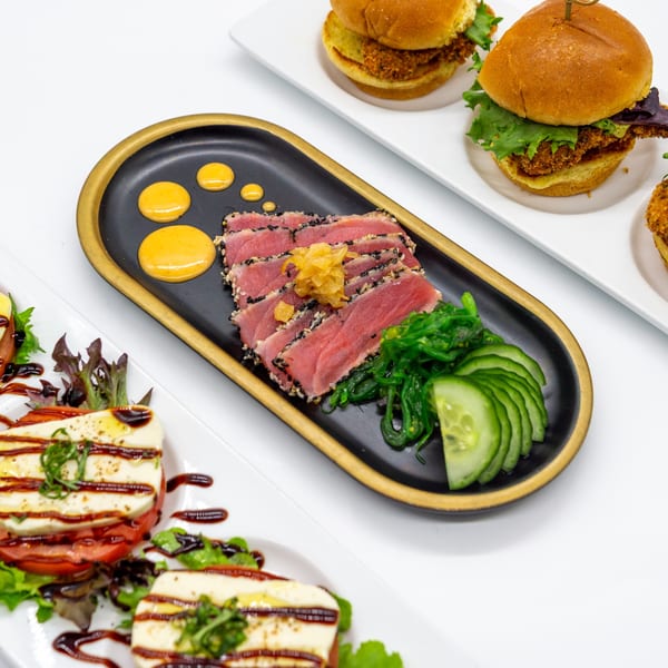 Seared tuna with seaweed salad, cucumber, and sauce, alongside sliders and caprese salad.